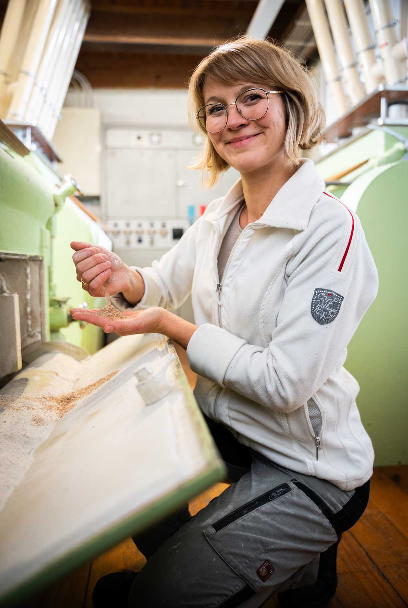 Müllerin in Berufsbekleidung neben Maschinen